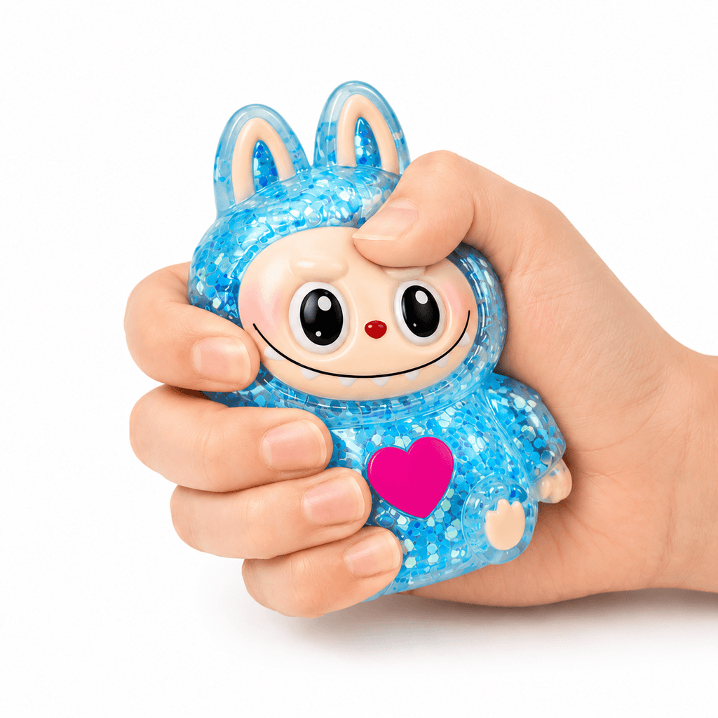 Main pressant un squishy personnage bleu pailleté kawaii à texture ultra douce et effet slow rising.